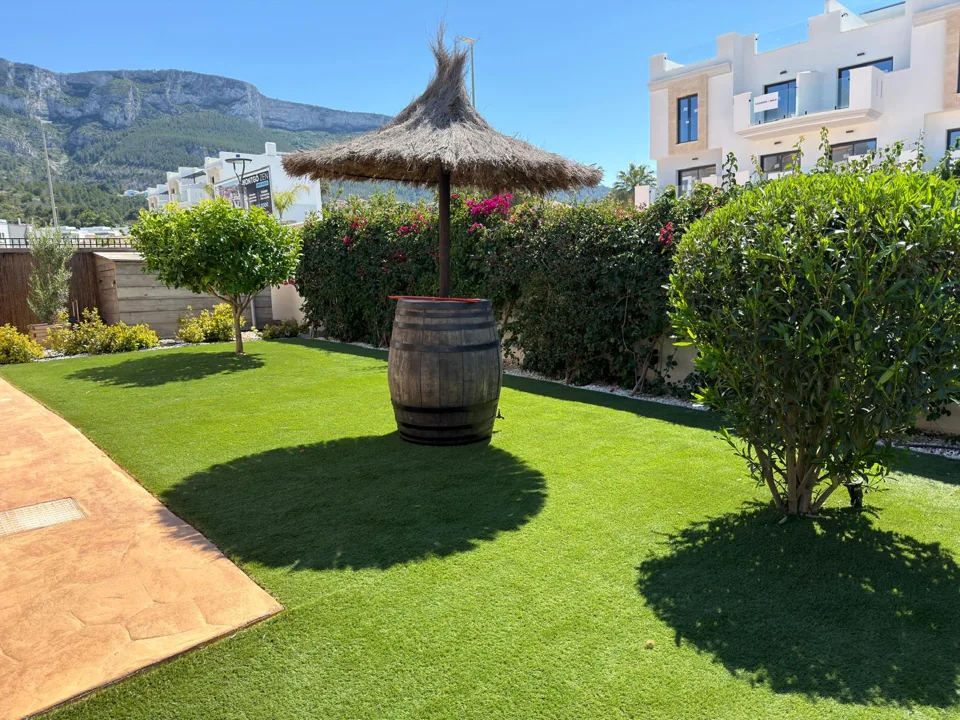Neatly trimmed hedges beside a green lawn and shaded terrace